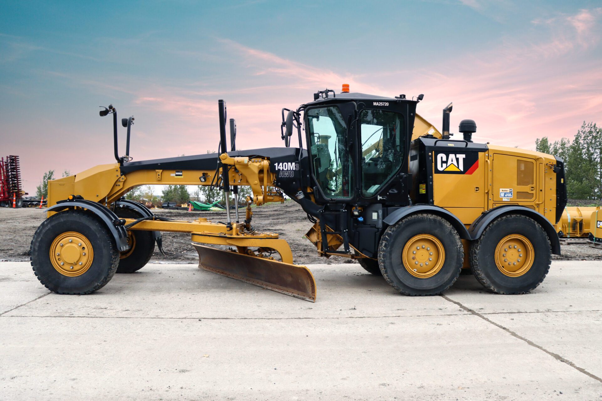 A yellow cat construction machine parked on a concrete surface, showcasing its robust design and vibrant color