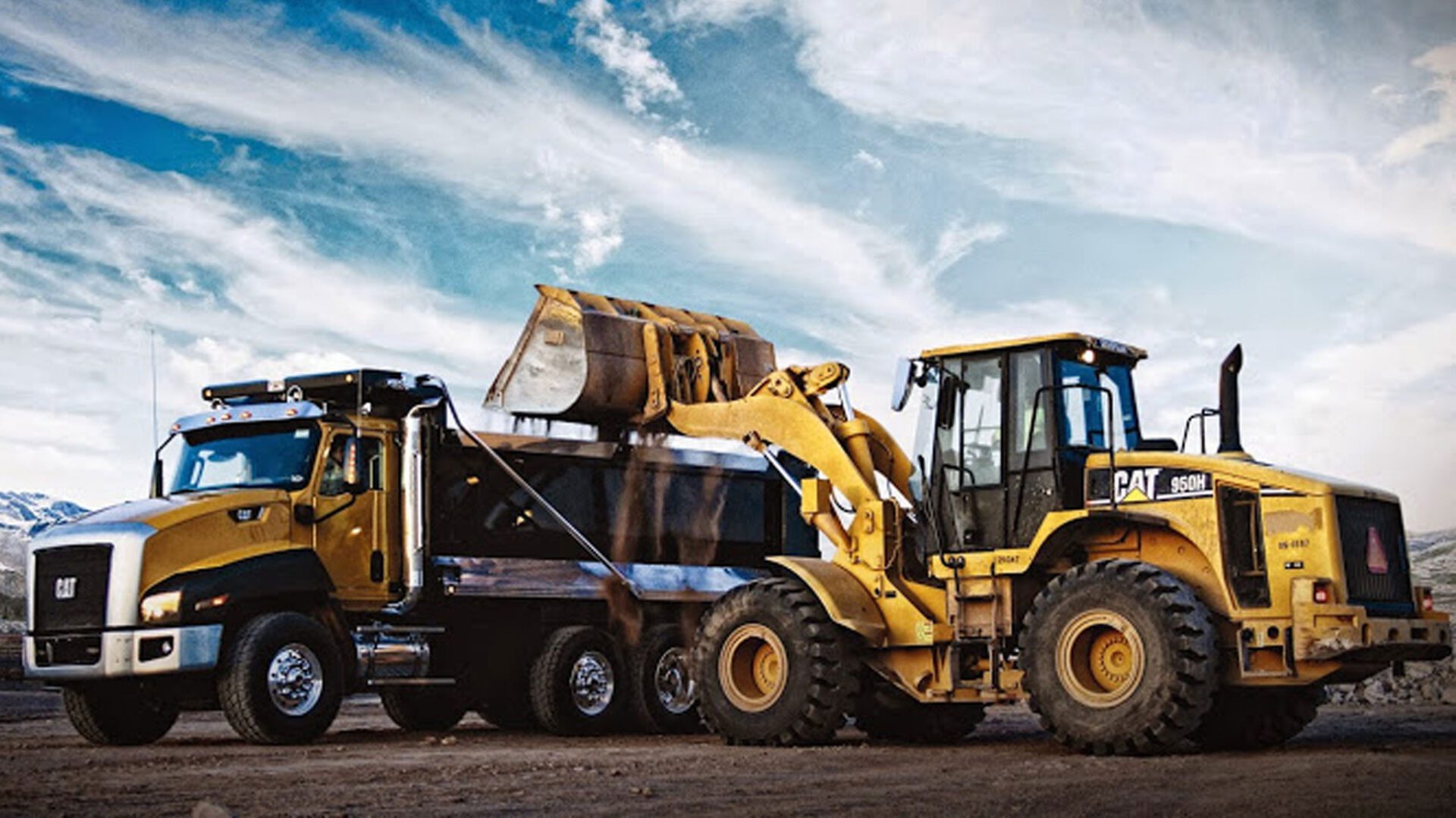 Yellow bulldozer dumping sand into the big yellow truck